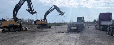 Excavators and flat deck trucks at a job site