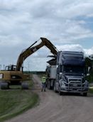 Excavator loading a truck on a gravel road