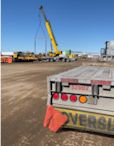 Rear of a flat deck trailer with a crane at a work site